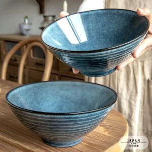 Bol à ramen Towada bleu tenu au-dessus d'un second bol sur une table