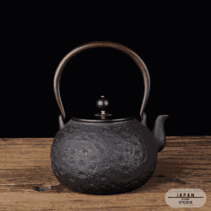 Théière en fonte Daimyo noire texturée sur une table, premier modèle