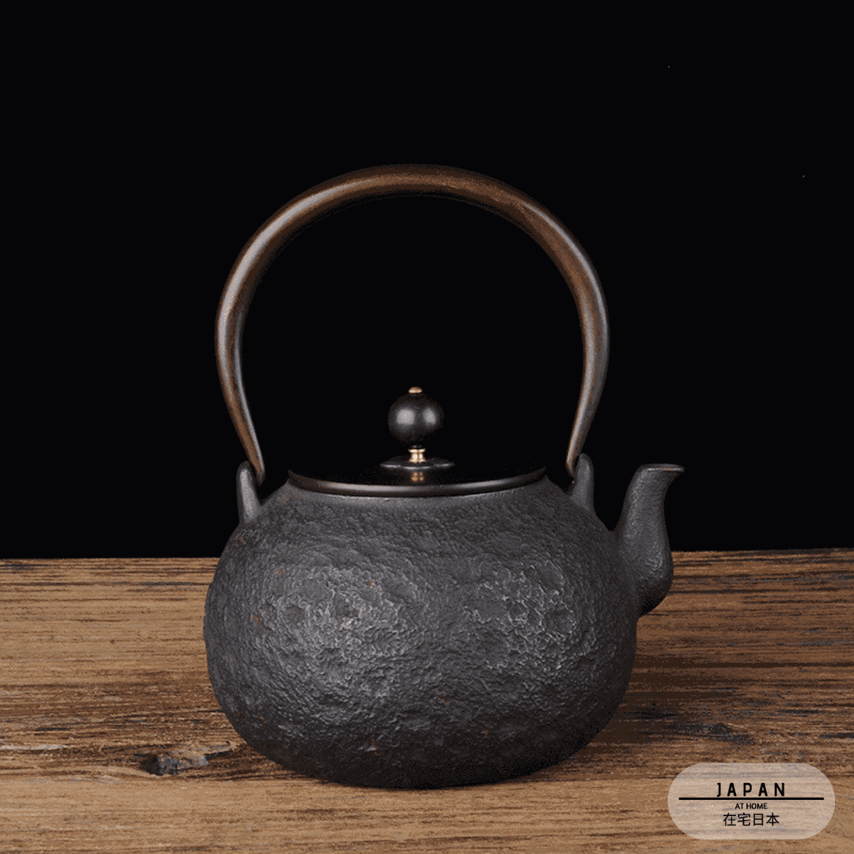 Théière en fonte Daimyo noire texturée sur une table, premier modèle