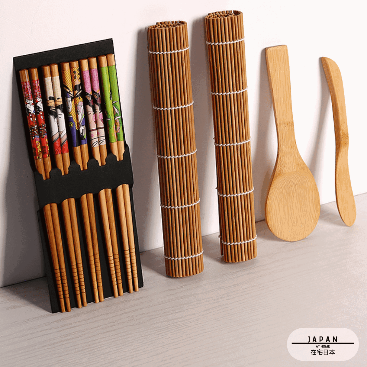 Kit sushi vu de biais : baguettes à motifs, nattes enroulées et ustensiles en bambou