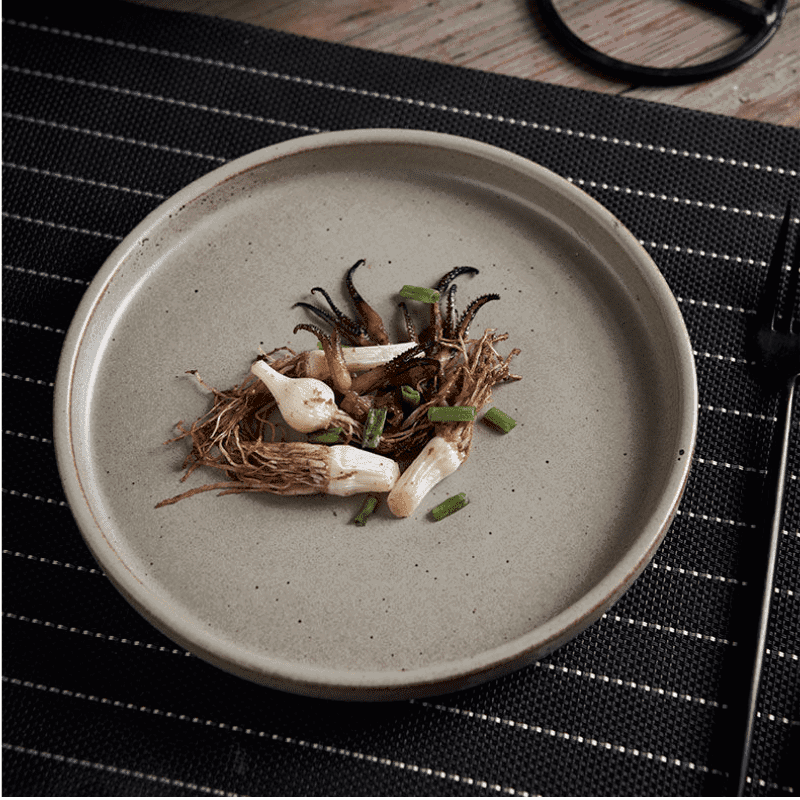 Assiette japonaise Kuba beige garnie de légumes sur un set rayé noir