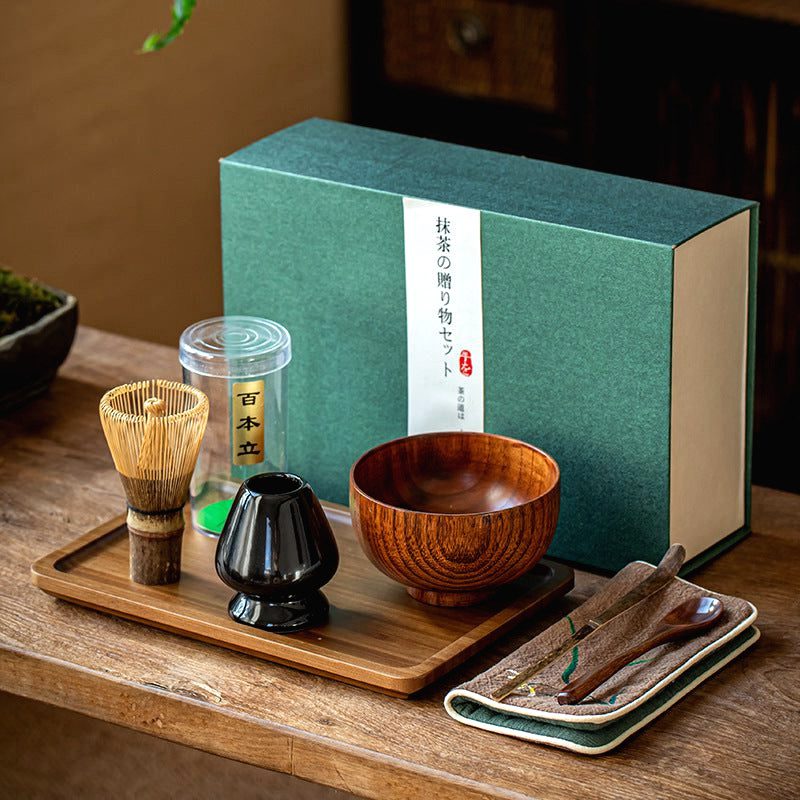 Coffret matcha avec bol en bois, fouet et porte-fouet noir devant sa boîte verte
