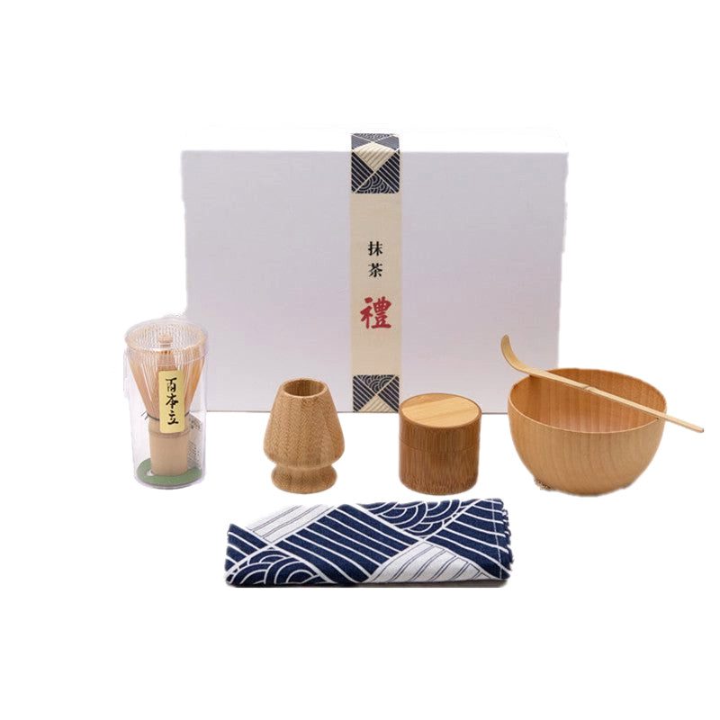 Accessoires du kit matcha alignés sur un tissu bleu, coffret fermé derrière