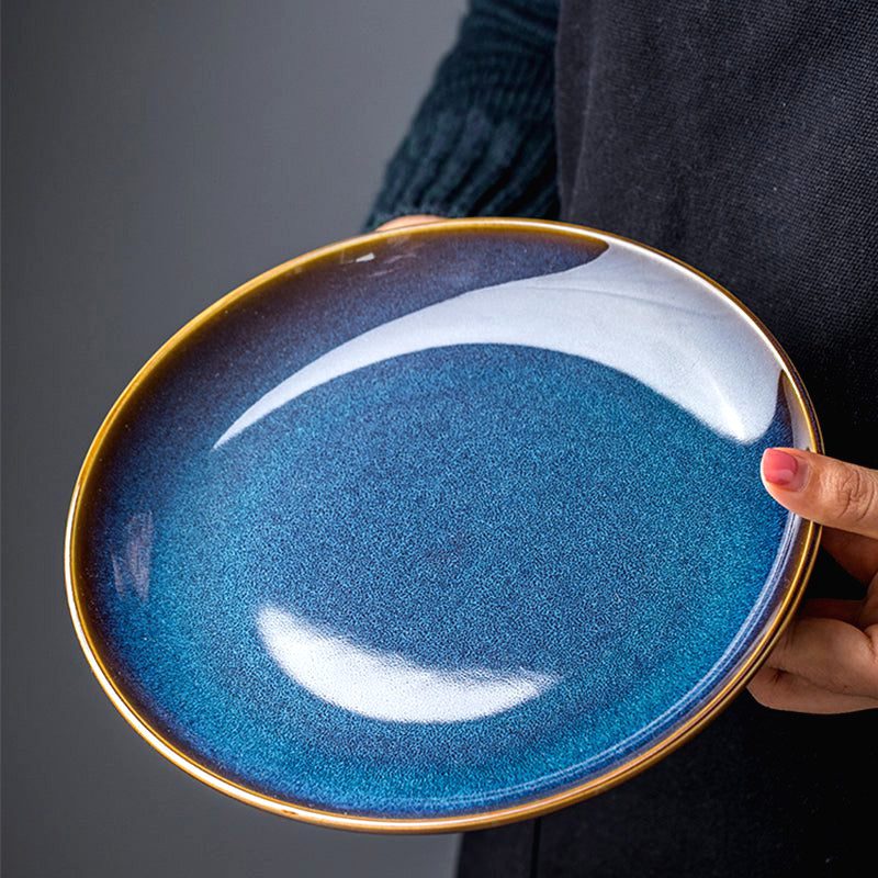 Assiette japonaise Tatsuzo bleue tenue d'une main, vue de dessus