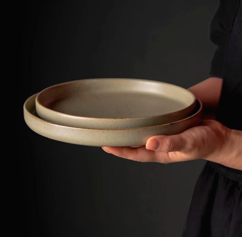 Deux assiettes japonaises Kuba empilées tenues d'une main sur fond noir